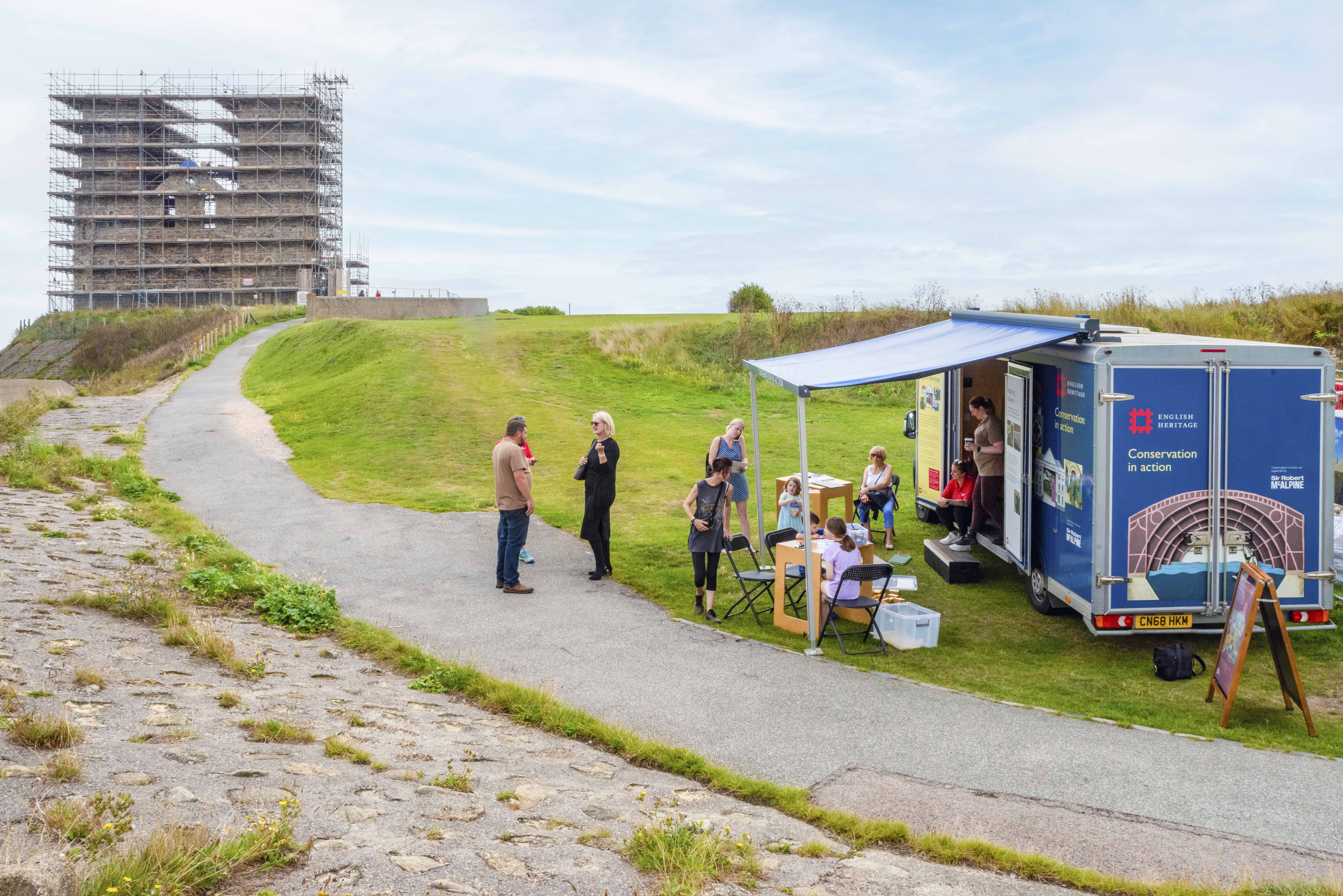 Photo of a group of people next to an English Heritage Conservation In Action van at Reculver Towers and Roman Fort