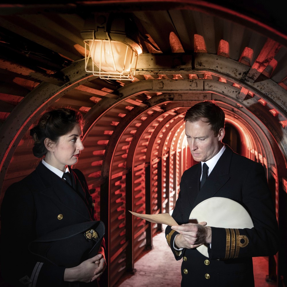 Photo of two people dressed in Second World War naval uniforms in the tunnels at Dover Castle