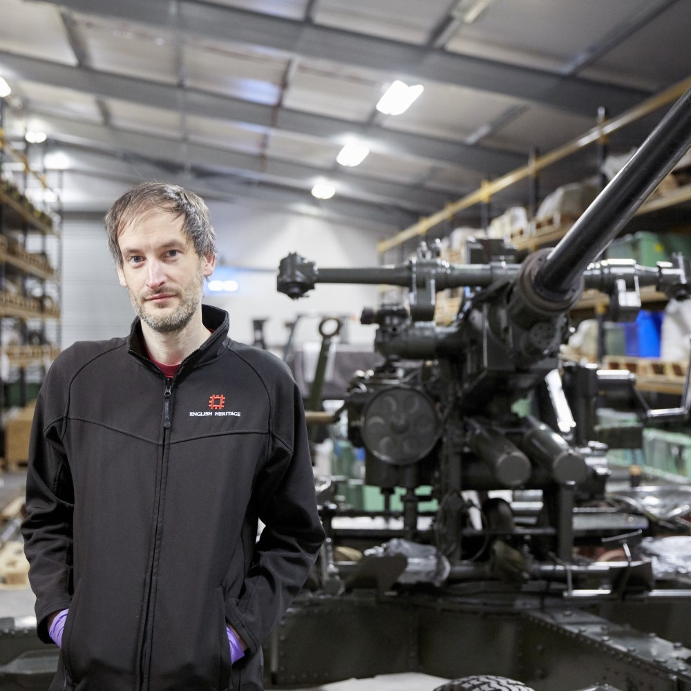 Photo of Curator of Collections Ian Leins standing next to a historical artillery gun at Temple Cloud in Somerset