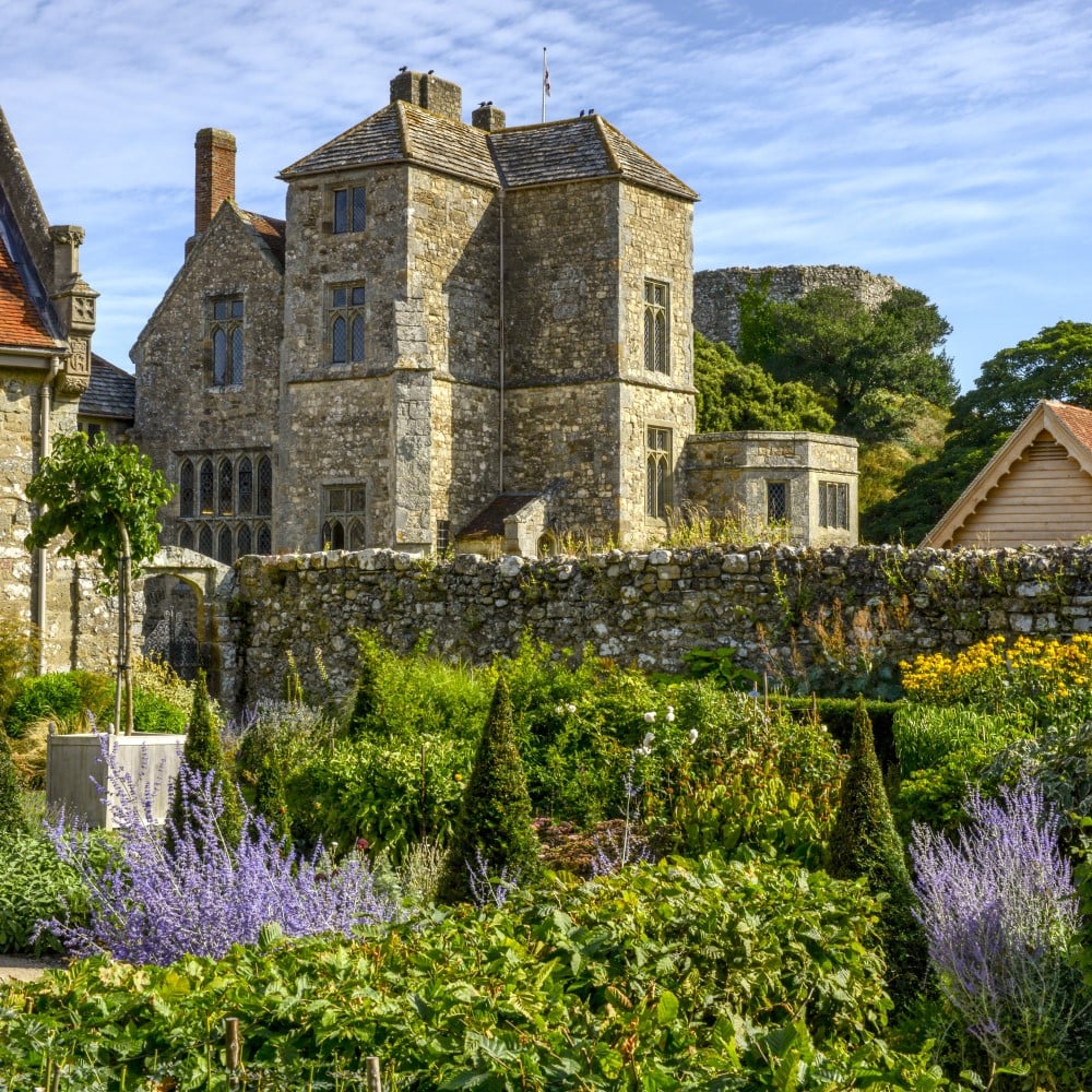 Photo of Carisbrooke Castle on a sunny day with its garden in the foreground