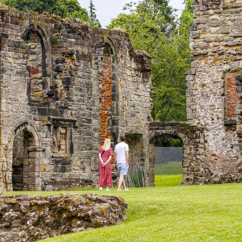 Photo of two people walking around the remains of Ashby de la Zouch Castle