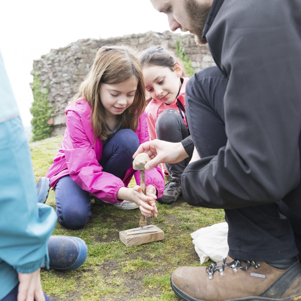 Photo of an adult supervising two children to start a fire at Beeston Castle and Woodland Park