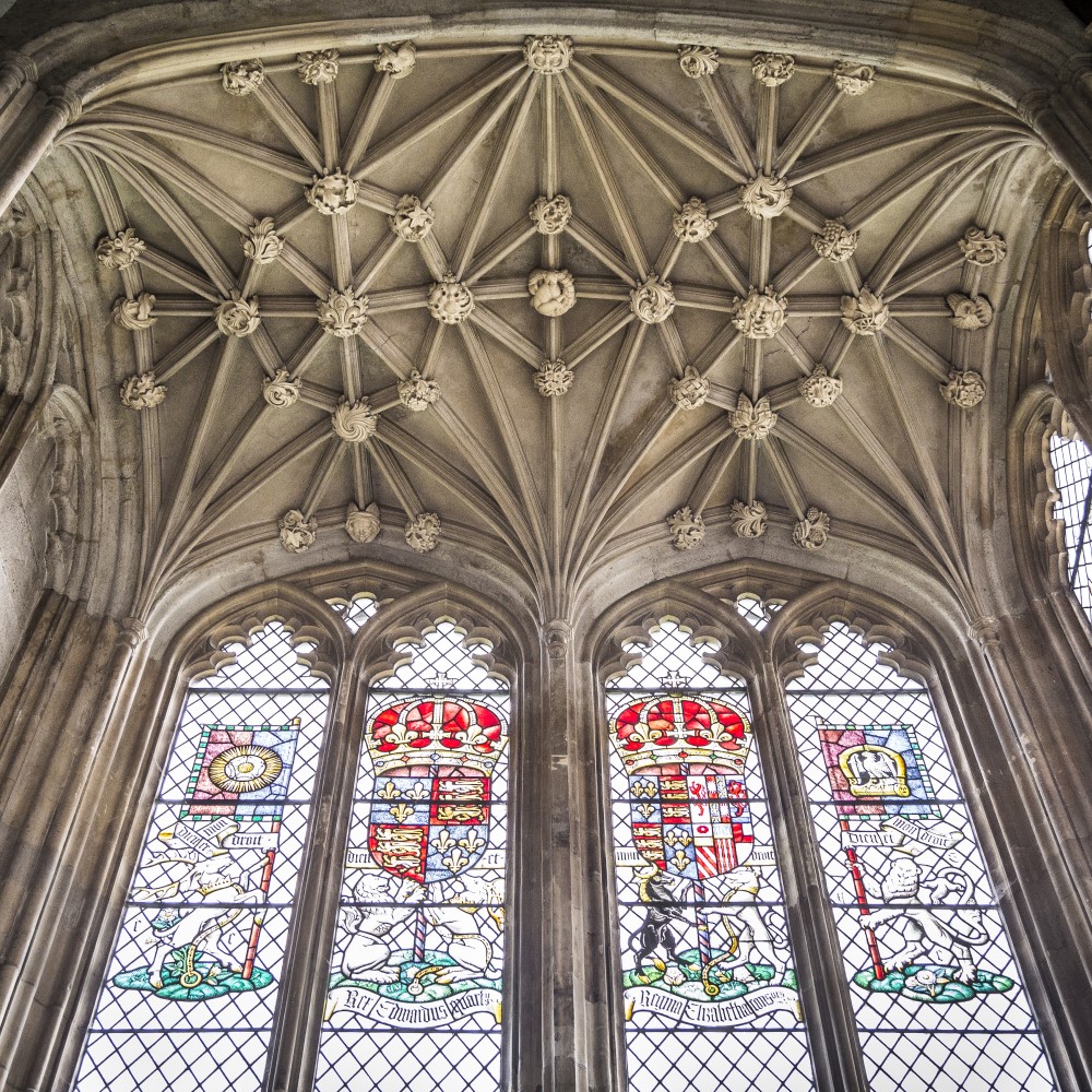 Photo looking up at stained-glass windows and a vaulted ceiling at Eltham Palace