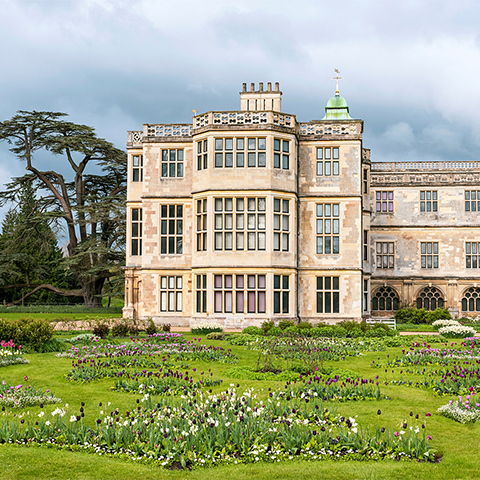 Photo of the exterior of Audley End House on a cloudy day with the gardens in the foreground