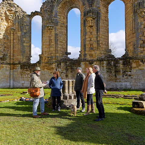 Image: tour guide and visitors at Byland Abbey