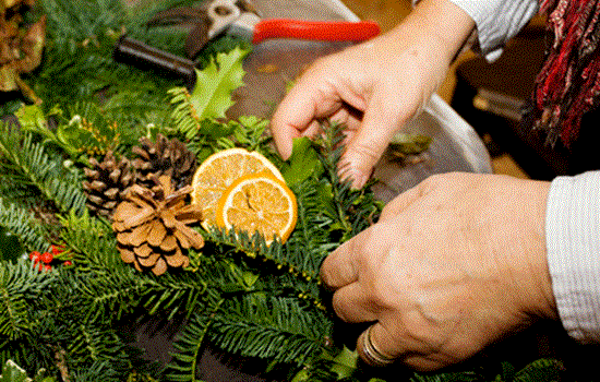 A close-up photograph of someone making a Christmas wreath. A close-up photograph of someone making a Christmas wreath.