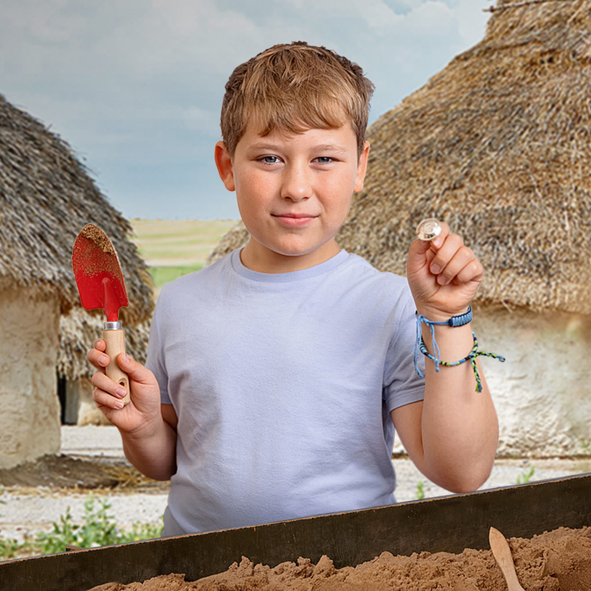 Boy holding trowel and object he has excavated